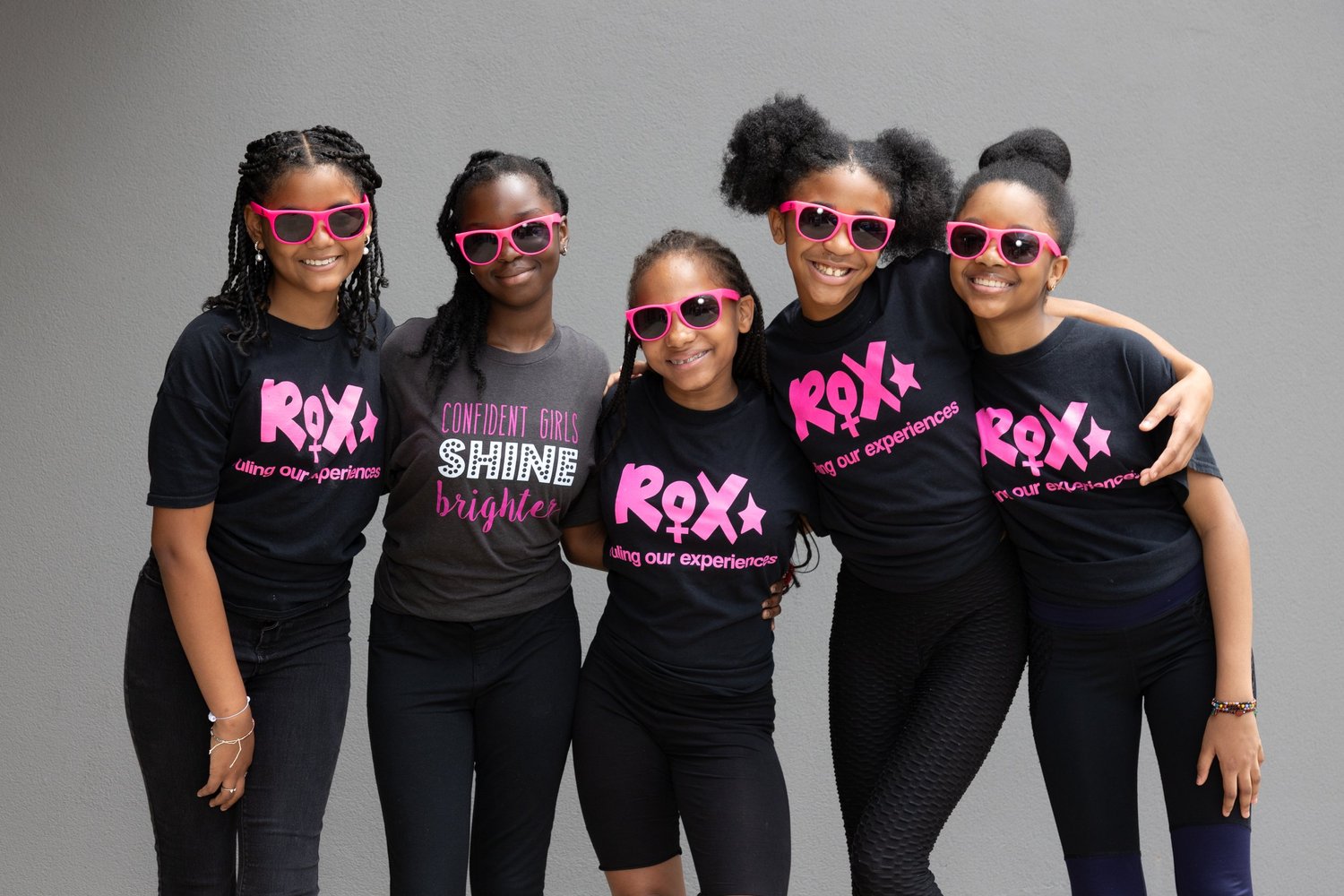 ROX girls arm-in-arm in pink sunglasses, smiling